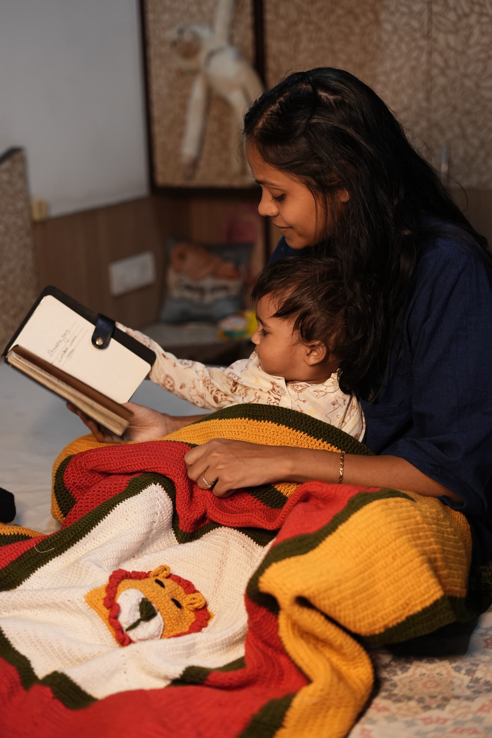 Cozy Cub crochet blanket with a lion face, mustard, red, and olive stripes, and corner tassels